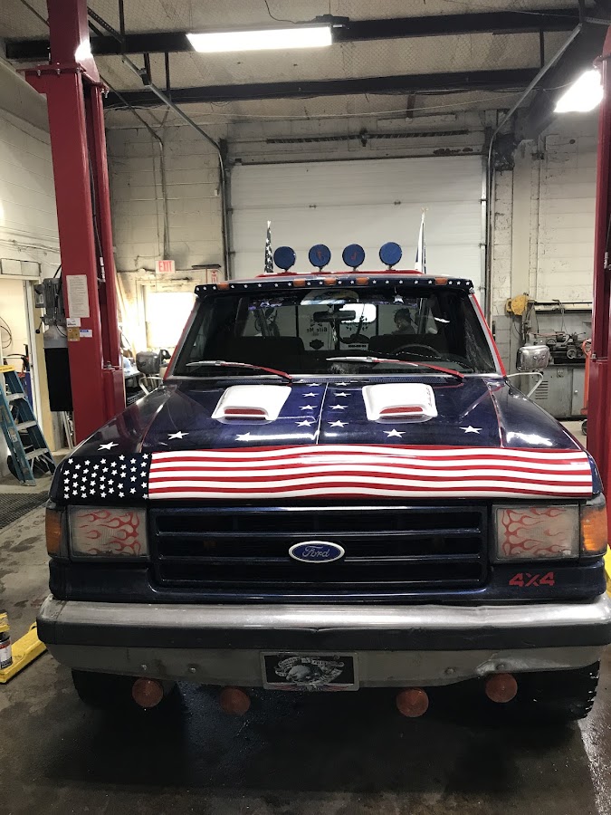 A Ford truck with a hand-painted American flag hood inside the All American Auto & Fleet shop